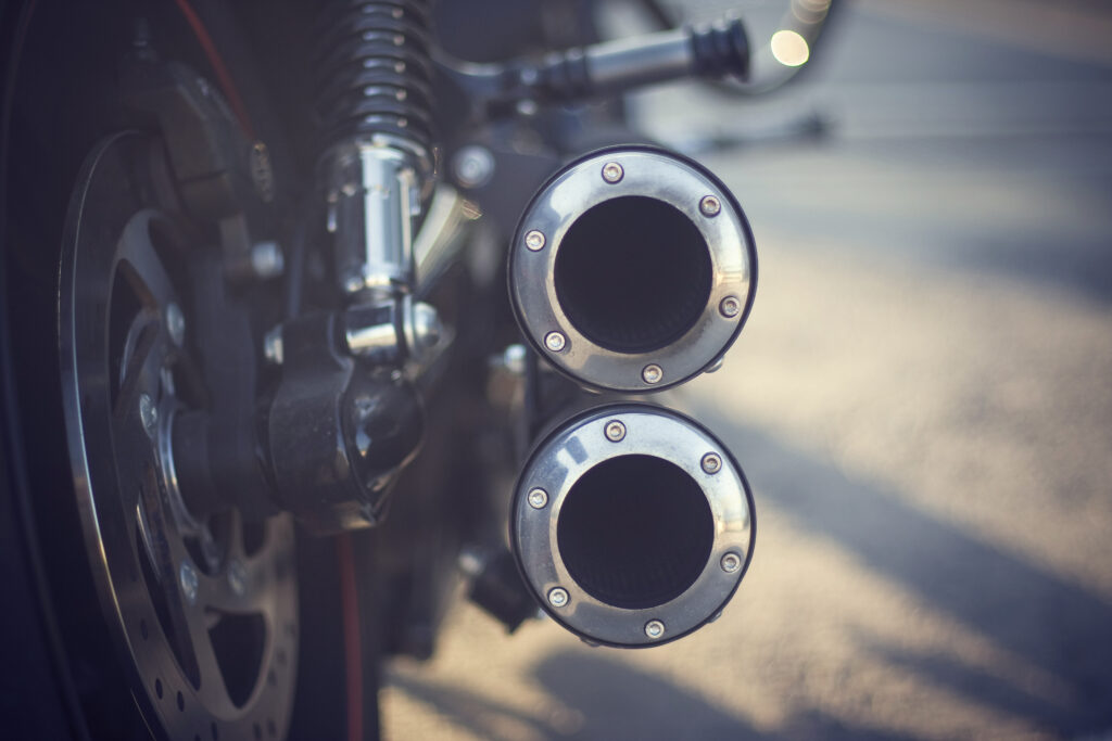 Close-up of motorcycle exhaust pipes and rear wheel.